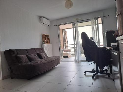 un salon avec un canapé et une chaise dans l'établissement Appartement T2 avec terrasse, 5 min de la plage, à Fréjus