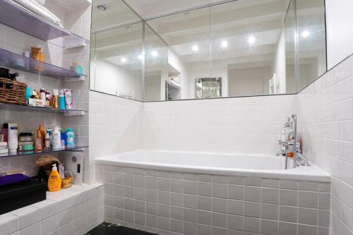 une salle de bain blanche avec une baignoire et un miroir dans l'établissement Chic Apartment with Private Terrace, à Paris