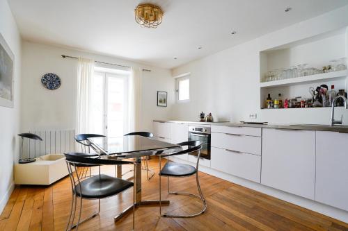 une cuisine avec des armoires blanches et une table et des chaises dans l'établissement Chic Apartment with Private Terrace, à Paris