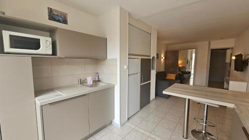 une petite cuisine avec un comptoir et un micro-ondes dans l'établissement Grand studio rénové avec terrasse et clim !, au Cap d'Agde