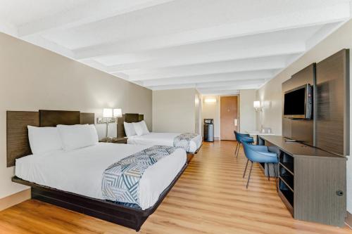 a hotel room with two beds and a flat screen tv at Red Carpet Inn & Suites in Philadelphia