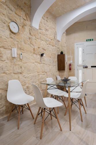 a dining room with a glass table and white chairs at Blue Hues Katerina - House of Character in Qormi