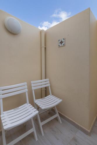 two white chairs sitting next to a wall with a clock at Blue Hues Katerina - House of Character in Qormi