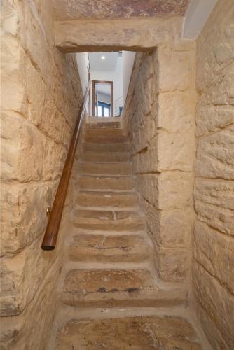 a staircase in a building with a stone wall at Blue Hues Katerina - House of Character in Qormi