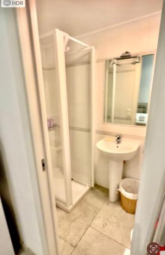 une salle de bain blanche avec un lavabo et une douche dans l'établissement monaco à 30 secondes et belle terrasse très calme, à Beausoleil