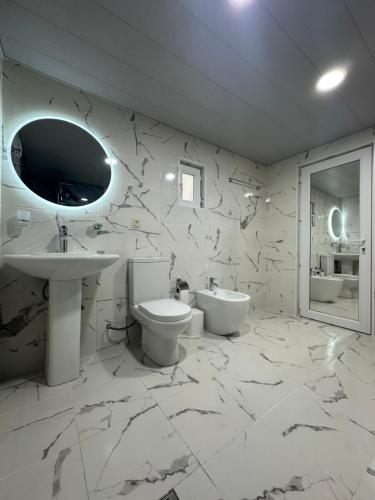 a white bathroom with a sink and a toilet at Maia's house in Batumi