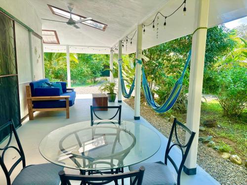 a porch with a glass table and chairs and a hammock at Casa Del Bambu in Puerto Jiménez