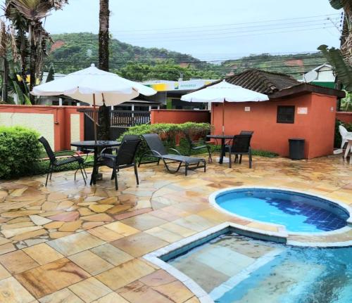 Un patio con piscina, sillas y sombrilla. en Novo Duplex em condomínio com piscina Juquehy, en São Sebastião