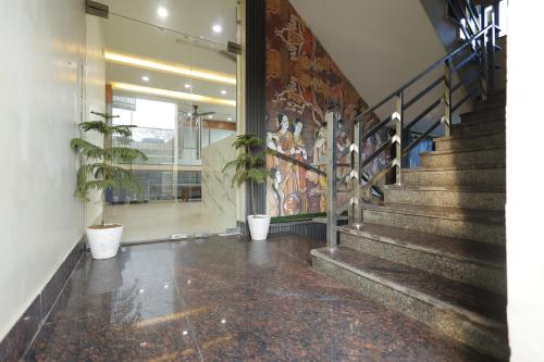 a hallway with stairs and potted plants in a building at Silver Oaks Inn in Mathura