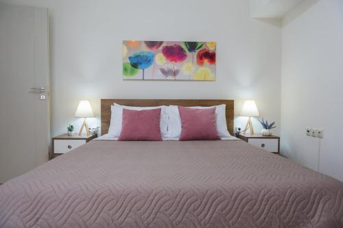 a bedroom with a large bed with pink pillows at Filora Apartment in the city center in Heraklio Town