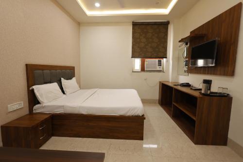 a bedroom with a bed and a desk with a television at Silver Oaks Inn in Mathura