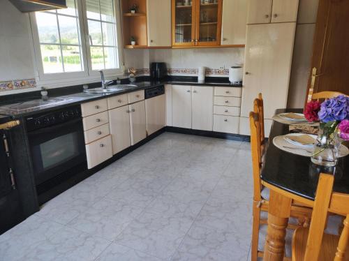 a kitchen with white cabinets and a black appliances at El Rincón Del Silencio in Moucide