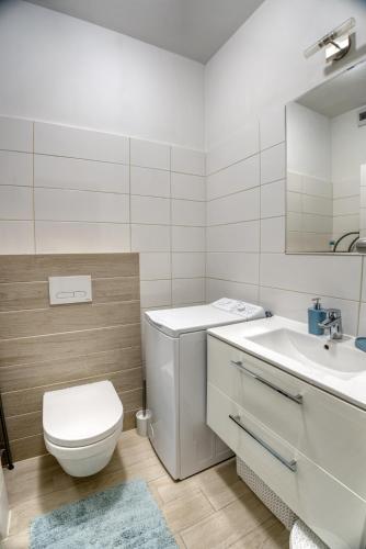 a white bathroom with a toilet and a sink at Aquamarina Onyx 18 in Międzyzdroje