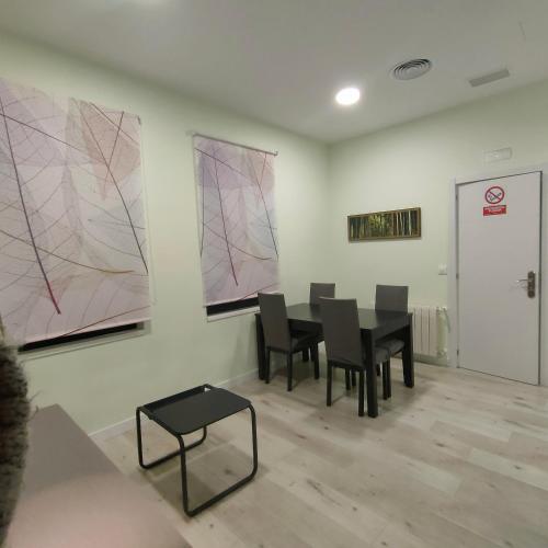 a room with a table and chairs and paintings on the wall at Apartamentos Megaleon in Segovia