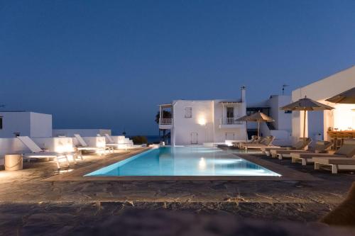 a swimming pool with chairs and umbrellas at night at KAMEO, Antiparos in Andiparos