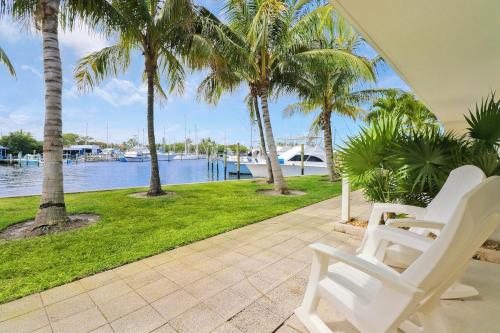 Un par de sillas blancas en un patio con palmeras. en Sailfish Suites 6 - pet friendly waterfront, en Stuart