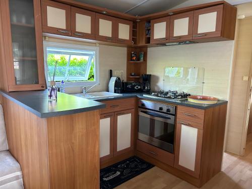 une cuisine avec des armoires en bois et un four à plaques de cuisson dans l'établissement Mobil Home Bord de Mer, à Le Port-des-Barques