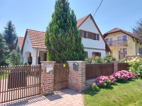 a fence in front of a house with a tree at Négy Évszak Apartmanház in Zalakaros
