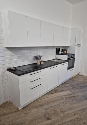 a kitchen with white cabinets and a black counter top at Domu Oltremare in Selargius