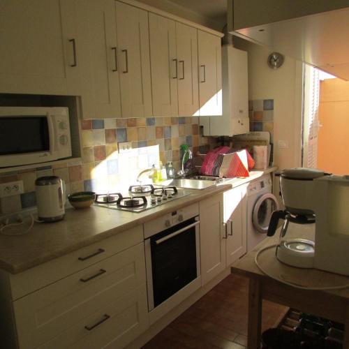 une cuisine avec des armoires blanches et un four à plaques de cuisson dans l'établissement Deux pièces rare avec vue, à Roquebrune-Cap-Martin