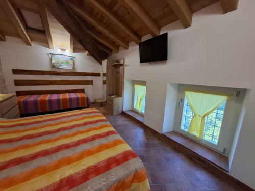 a bedroom with a bed and two windows and a television at Il Castellaro ai Sassi in Guiglia