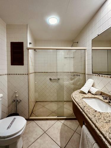 a bathroom with a shower with a toilet and a sink at Hotel Dominguez Plaza in Nova Friburgo