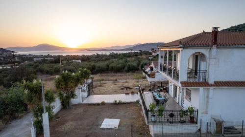 a woman sitting on a balcony of a house with the sunset at Villa Aelia Luxury Maisonette in Salamís