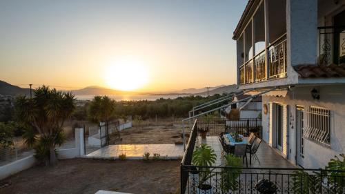 a sunset from the balcony of a house with the sun setting at Villa Aelia Luxury Maisonette in Salamís