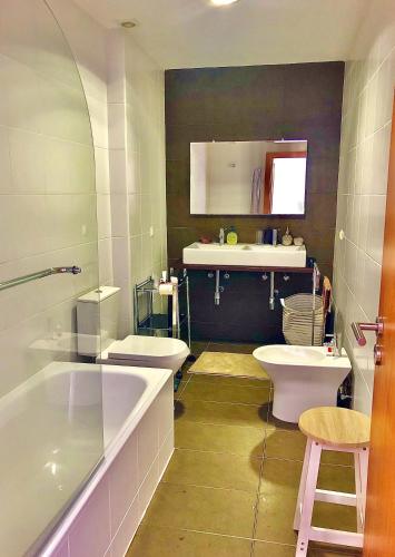 a bathroom with two toilets and a sink and a tub at Oceanus in Horta