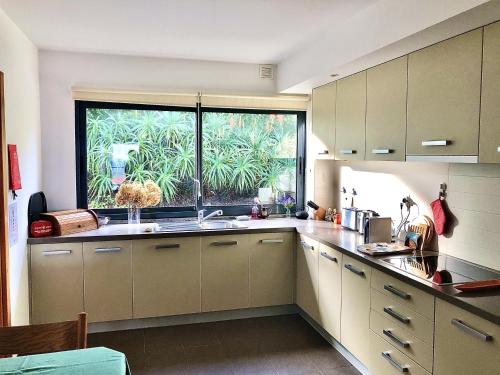 een keuken met een wastafel en een groot raam bij Oceanus in Horta