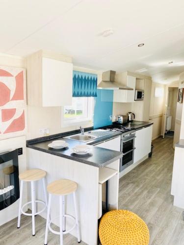 a kitchen with a counter and two stools in it at Haven, Cala Gran caravan park, privately owned in Blackpool