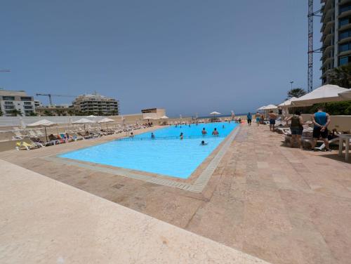 a large swimming pool on a beach with people in it at FortCambridge 2BR, pool, Terrace in Sliema