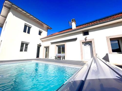 a swimming pool in front of a white house at La villa de Julien avec piscine in Aureilhan