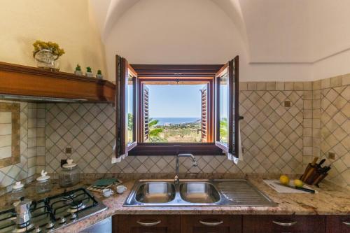 a kitchen with a sink and a window at Dammuso Meraki in Pantelleria
