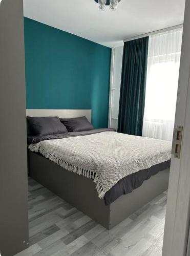 a bedroom with a bed with a blue wall at Apartament Nina in Bucharest