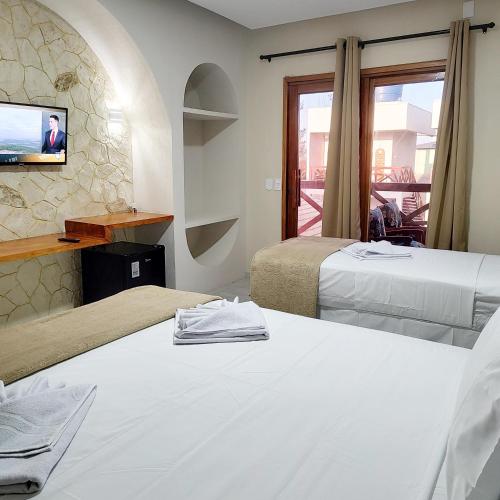 a hotel room with two beds and a tv at Villa Dubai Pousada, Restaurante e Pizzaria in Luis Correia