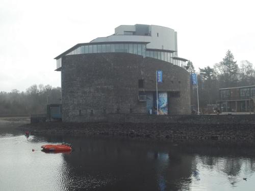 a building with a red boat in a body of water at Glenfern Guest House and a separate Cottage with its own private hot tub in Balloch