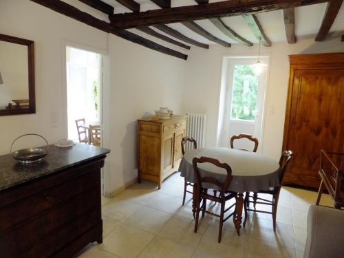 une cuisine avec une table et des chaises dans une pièce dans l'établissement La petite maison au bord de l'Orne, à Putanges