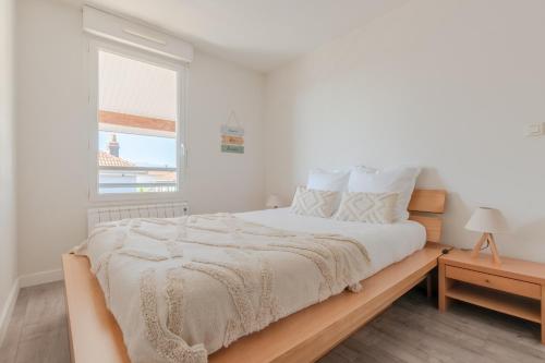 une chambre blanche avec un grand lit et une fenêtre dans l'établissement Le Cosy Tarbais - Parking - Balcon - Vue Pyrénées, à Tarbes