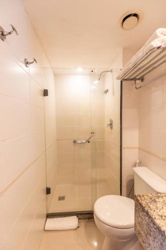 a bathroom with a toilet and a glass shower at Barra Premium - flat com serviços, recepção 24 horas, piscina, academia e balsa para praia! in Rio de Janeiro