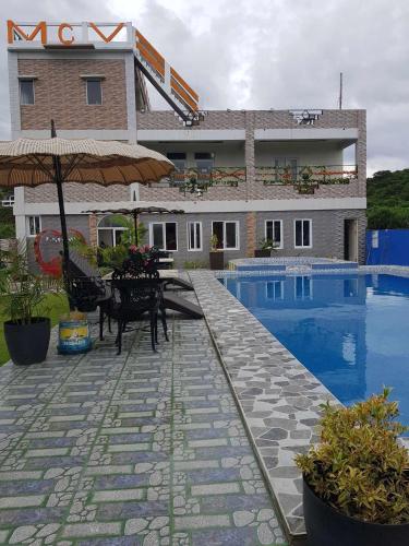 a hotel with a patio with an umbrella and a pool at Mountain cove villa in Pagudpud
