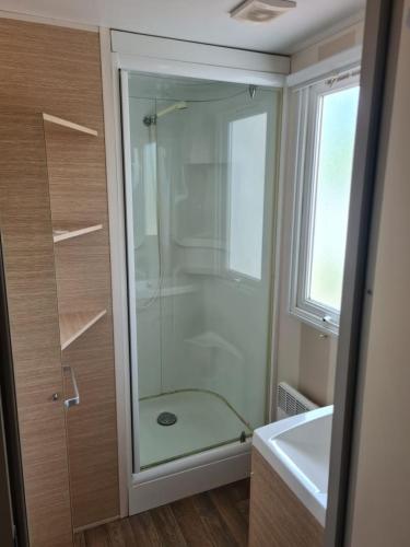 une douche avec une porte vitrée dans une salle de bain dans l'établissement Mobil home camping Siblu des embruns, à Lège-Cap-Ferret