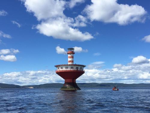 a lighthouse in the middle of a body of water at Hotel Le Pionnier in Tadoussac