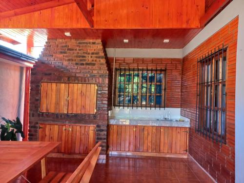 a kitchen with wooden cabinets and a brick wall at Rincón soñado para 8 personas in Puerto Iguazú