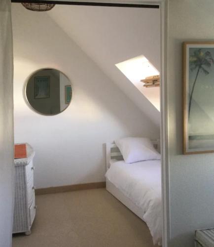 une chambre avec un lit blanc et un miroir dans l'établissement duplex vue mer grande plage,coeur cente ville, à Quiberon