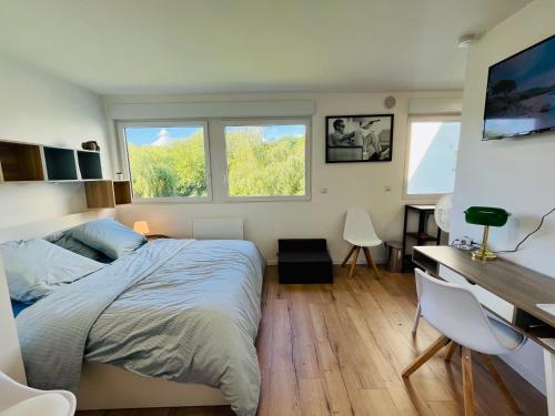 une chambre avec un lit et un bureau et deux fenêtres dans l'établissement Le studio du jardin Public centre secteur VIP Luxe - vue panoramique, à Béthune