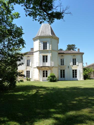 une grande maison blanche avec une tour sur une pelouse dans l'établissement Le gîte des grands arbres, à Montcaret