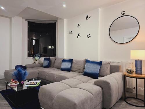 a living room with a gray couch and blue pillows at Abbey Corner by Nivaas 3-Located in the heart of the city centre-5 minute walk to train station-20 minutes to London via train in Reading