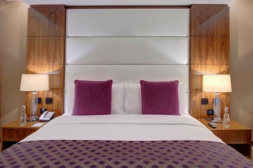 a bedroom with a large bed with purple pillows at Crowne Plaza Muscat OCEC by IHG in Muscat