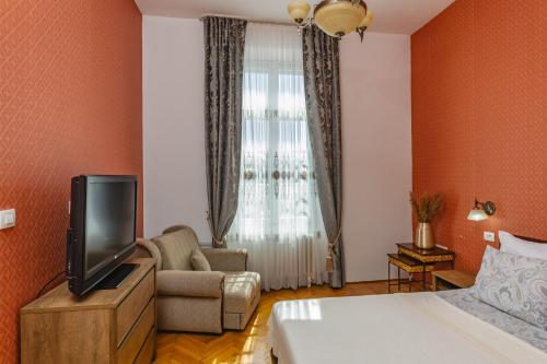 a hotel room with a bed and a tv and a couch at Le Petit Chateau in Bar